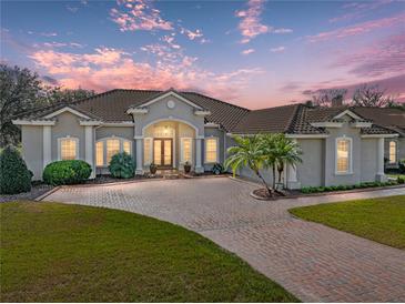 Beautiful single-story home with a tile roof, brick driveway and lush landscaping at 13854 Thoroughbred Dr, Dade City, FL 33525