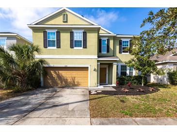 Two-story home featuring a two-car garage, well-maintained lawn, and freshly planted shrubbery under a clear, blue sky at 11539 Tangle Branch Ln, Gibsonton, FL 33534