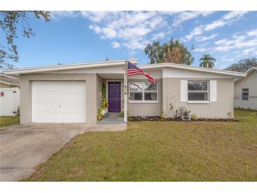 Charming single-story home featuring a manicured front lawn, single car garage, and a vibrant purple front door at 1773 Ezelle Ave, Largo, FL 33770