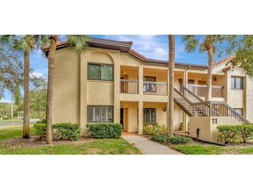 Inviting two-story condo showcases a charming facade with palm trees and well-maintained landscaping at 1801 E Lake Rd # 11A, Palm Harbor, FL 34685