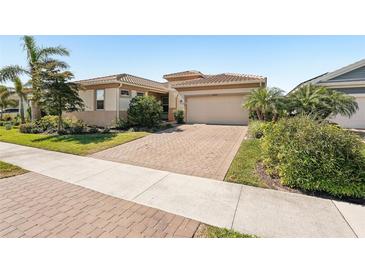 Inviting single-story home featuring a manicured lawn, a paver driveway, and a two-car garage at 20237 Bandera Pl, Venice, FL 34293