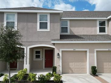 Charming townhouse featuring a private garage, manicured landscaping, and a welcoming front entrance at 2411 Paravane Way, Wesley Chapel, FL 33543