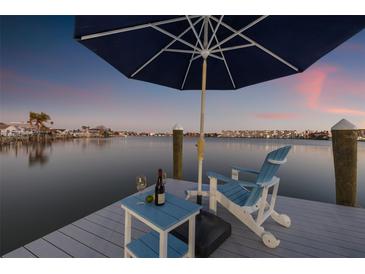 Relaxing waterfront view from the dock with an umbrella, table and chair at sunset, perfect for enjoying the scenery at 309 180Th E Ave, Redington Shores, FL 33708