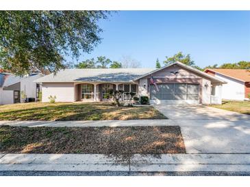 Charming single-story home with a well-maintained lawn, inviting front porch, and attached two-car garage at 8204 Reynolds Dr, Hudson, FL 34667