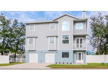 Three-story home with a gray siding, white trim, a two-car garage, and a well-manicured lawn at 320 Georgia Ave, Crystal Beach, FL 34681