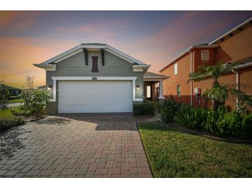 Charming home featuring a brick driveway and a two-car garage with an elegant stucco facade at 17596 Terrazzo Way, Land O Lakes, FL 34638