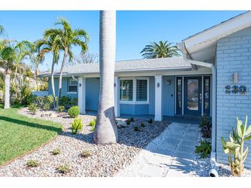 Inviting single-story home with stone pathway, manicured garden and a vibrant color scheme at 230 S Julia Cir, St Pete Beach, FL 33706