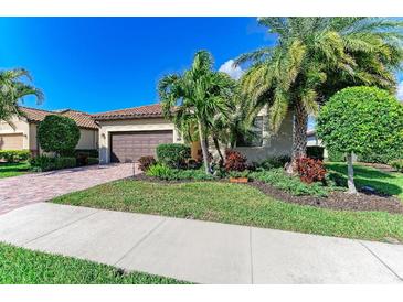 Charming home featuring a lush landscaped yard and a paver driveway leading to the attached garage at 7115 Marsh View Ter, Bradenton, FL 34212