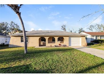 Charming home with a well-manicured front yard, complemented by a driveway and mature landscaping at 7825 Bolam Ave, New Port Richey, FL 34653