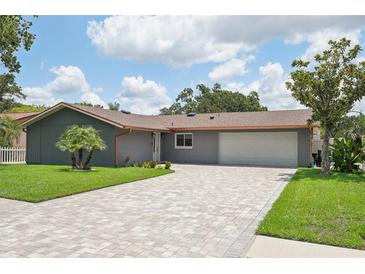 Charming one-story home with brick driveway, well-manicured lawn, and beautiful landscaping at 105 Country Villas Dr, Safety Harbor, FL 34695