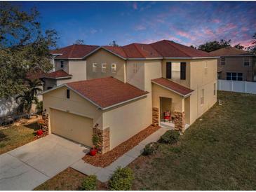 Two-story home with a red tile roof, neutral stucco, stone accents, and a two-car garage at 19609 Timberbluff Dr, Land O Lakes, FL 34638
