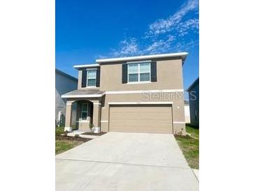 Two-story home featuring a neutral-colored exterior and an attached two-car garage at 2714 Lotus Flower Trl, Wesley Chapel, FL 33543