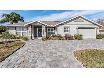 Charming single-story home featuring a paver driveway, manicured landscaping, and attached two car garage at 29307 Schinnecock Hills Ln, San Antonio, FL 33576