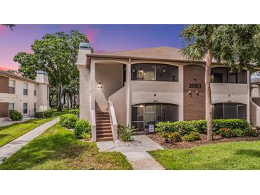 Inviting exterior view of the home featuring a screened porch, lush landscaping, and well-maintained grounds at 2983 Bonaventure Cir # 204, Palm Harbor, FL 34684