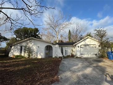 A single-Gathering home with a front yard and an attached garage in a residential area with a cloudy sky at 4233 Abaco Ct, New Port Richey, FL 34653