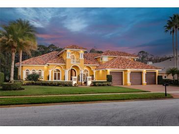 Stunning Mediterranean-style home with a terracotta roof, lush landscaping, and a three-car garage at 4873 Quill Ct, Palm Harbor, FL 34685