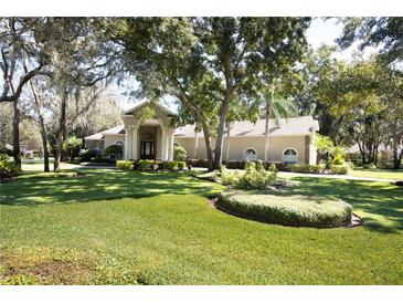 Stunning single-story home boasts lush landscaping, a circular driveway, and an inviting columned entryway at 6222 Kingbird Manor Dr, Lithia, FL 33547