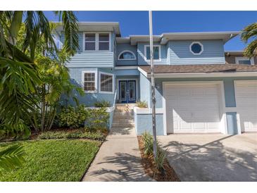 Charming light blue two-story home with a two-car garage and beautifully landscaped front yard at 7284 Pebble Beach Ln, Seminole, FL 33777