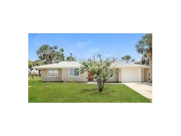 Charming single-story home featuring a well-manicured lawn and tropical landscaping at 18663 Kerrville Cir, Port Charlotte, FL 33948