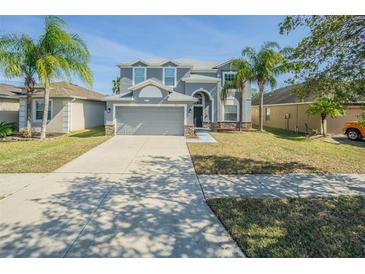 Two-story home featuring neutral paint, well-manicured landscaping, a two-car garage and an arched front entrance at 2111 Roanoke Springs Dr, Ruskin, FL 33570