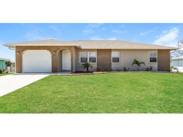 Charming single-story home featuring a well-maintained lawn, brick accents, and an attached garage at 28 Caddy Rd, Rotonda West, FL 33947