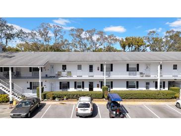 Exterior view of a two-story building with parking, landscaping, and balcony access at 300 Glennes Ln # 203, Dunedin, FL 34698