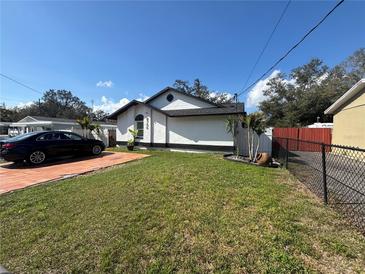 Charming single-story home features well-maintained lawn and a modern car parked on the driveway at 8706 N Boulevard, Tampa, FL 33604