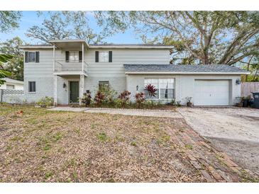 Charming two-story home with grey siding, brick accents, balcony, and a well-manicured lawn at 14803 Tulip Dr, Tampa, FL 33613