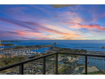 Expansive waterfront view from the condo balcony showing a harbor, parking lots, and a stunning sunset sky at 301 1St S St # 2104, St Petersburg, FL 33701