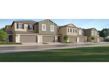 New townhomes showcase multi-tone exteriors, and attached garages across a manicured lawn at 36095 Joseph Blake St, Zephyrhills, FL 33541