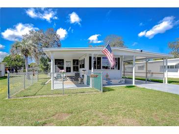 Charming single-story home featuring a fenced yard, covered porch, and an American flag waving proudly at 4529 Olive Dr, Zephyrhills, FL 33542