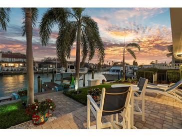 Waterfront backyard patio featuring outdoor seating, palm trees, boats, and a stunning sunset view at 4930 60Th S Ave, St Petersburg, FL 33715