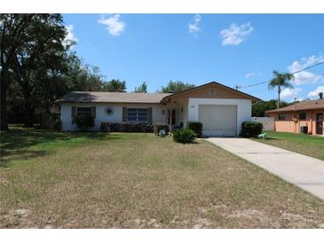 Charming single-story home featuring a well-kept lawn, mature trees, and an attached garage at 6188 Pinehurst Dr, Spring Hill, FL 34606