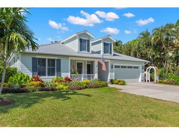 Charming two-story coastal home with a well-manicured lawn and colorful landscaping at 140 Miramar Ne Blvd, St Petersburg, FL 33704