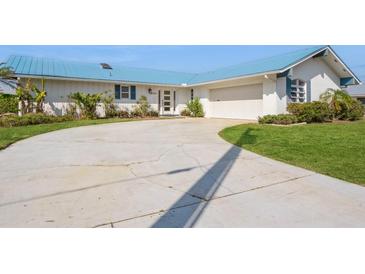 Charming single-story home with a driveway, front lawn, crisp white paint, blue shutters, and a matching light-blue metal roof at 2821 Coral Way, Punta Gorda, FL 33950