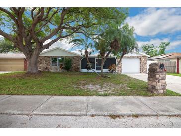 Charming single-story home features a stone facade and a well-maintained front yard with mature trees at 6304 Seabreeze Dr, Port Richey, FL 34668