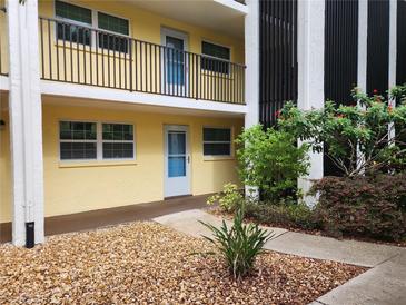 Inviting condo exterior with a yellow facade, black railings and lush landscaping at 821 Deleon Ct # 108, Dunedin, FL 34698