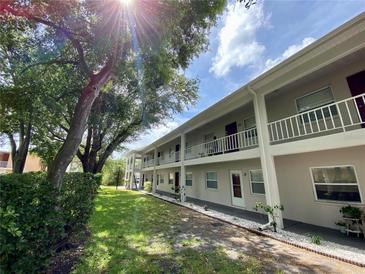 Light beige condo building with balconies, lush landscaping, and ample green space at 8304 Bardmoor Blvd # 104, Seminole, FL 33777