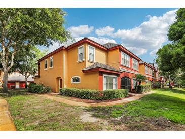 Tan townhome with red accents, lush landscaping, and a walkway at 2272 Chianti Pl # 4-0048, Palm Harbor, FL 34683