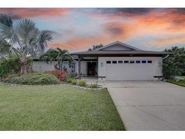 Single-story home with white exterior, landscaped yard, and a two-car garage at 2098 Swan Ln, Safety Harbor, FL 34695