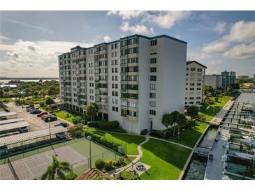 Aerial view of waterfront condo building with tennis courts, pool, and boat slips at 660 Island Way # 301, Clearwater Beach, FL 33767