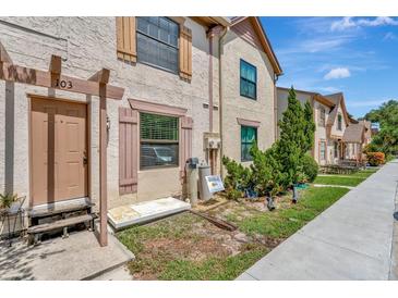 Tan two-story townhome with brown door, small yard, and walkway at 103 Brigadoon Dr, Clearwater, FL 33759