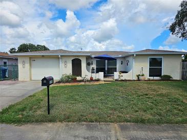 Inviting single-Gathering home with a lush front lawn, decorative accents, and a charming patio area at 1172 Chelsea Ln, Holiday, FL 34691