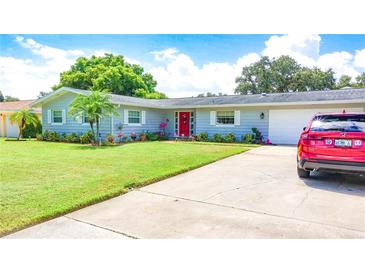 Ranch-style home with a red door, attached garage, and well-manicured lawn at 1847 Oak Lake Dr, Clearwater, FL 33764