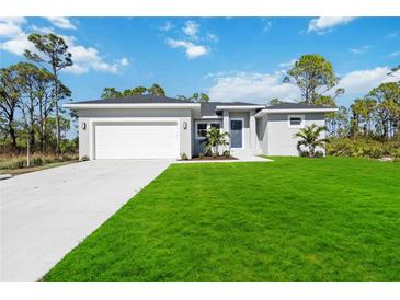 Newly built home with a white garage door and a lush green lawn at 9333 Hialeah Ter, Port Charlotte, FL 33981