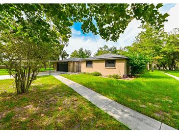 Tan house with carport, landscaped yard, and walkway at 11621 Colt Way, Hudson, FL 34669