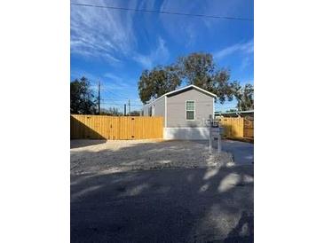 Single-wide manufactured home with wood fence and gravel driveway at 1925 Patriot Ln, Holiday, FL 34690