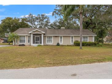 Single-story home with a screened porch and landscaped yard at 37351 Neighbors Path, Zephyrhills, FL 33542