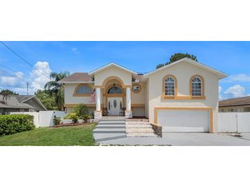 Tan two-story house with a two-car garage and landscaped yard at 15806 Adobe Dr, Hudson, FL 34667