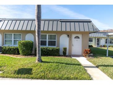 Inviting condo exterior, featuring a gray metal roof and well-manicured lawn at 11617 Boynton Ln, New Port Richey, FL 34654